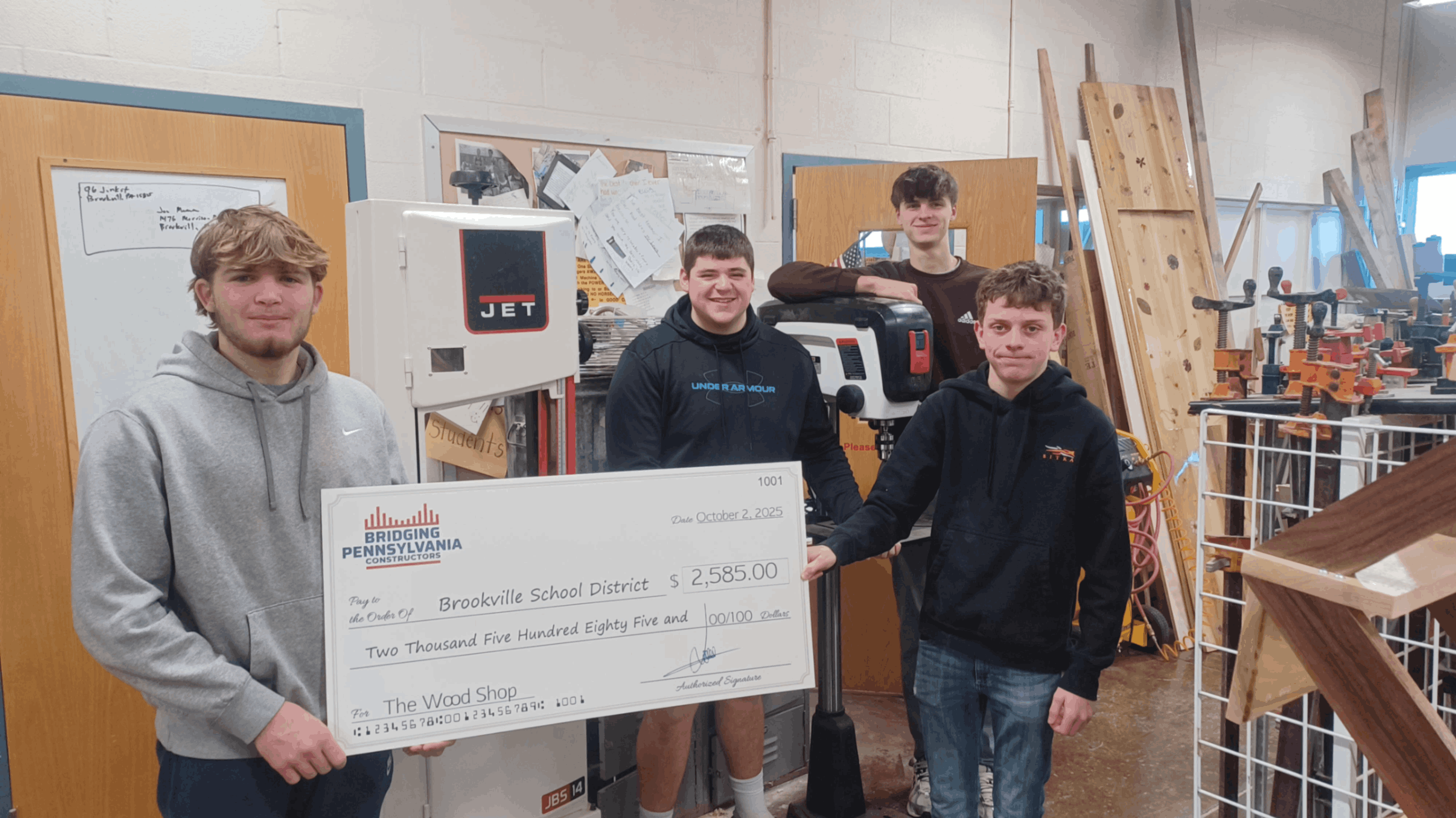 Woodshop students pose with a check presented by Bridging Pennsylvania Constructors and a new bandsaw that was purchased with the funds.